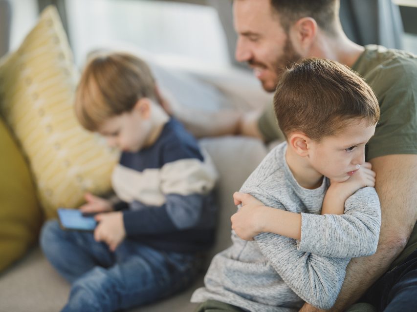 Parents on a sofa with a worried boy hugging himself